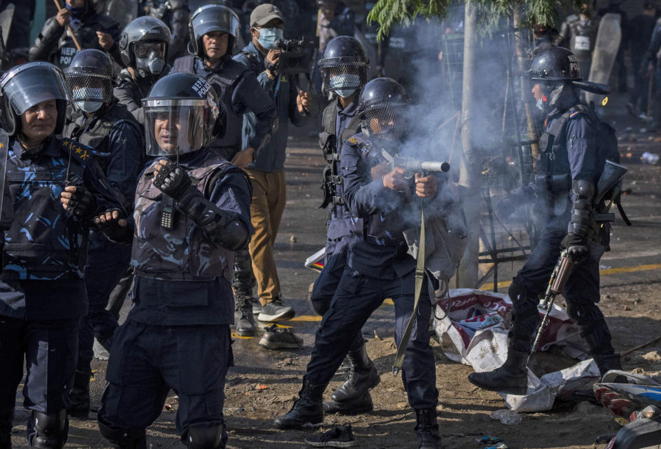 A policeman fires tear gas towards protesters during a rally demanding a restoration of Nepal's monarchy in Kathmandu, Nepal, Thursday, Nov. 23, 2023. Riot police used batons and tear gas to halt tens of thousands of supporters of Nepal's former king demanding the restoration of the monarchy and the nation's former status as a Hindu state. Weeks of street protests in 2006 forced then King Gyanendra to abandon his authoritarian rule and introduce democracy. (AP Photo/Niranjan Shrestha)