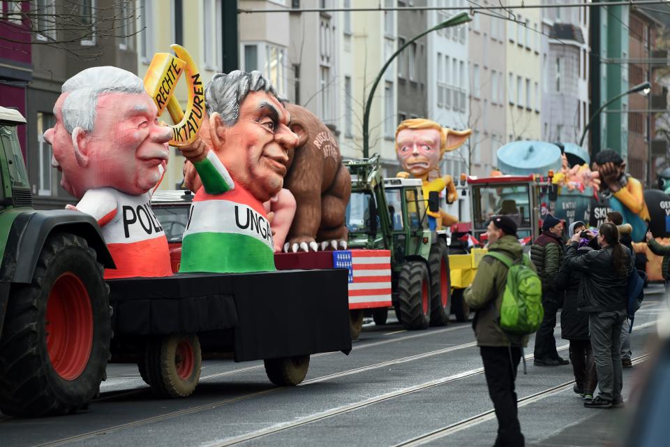 <p>People look at a carnival float, depicting Polish President Andrzej Duda and Hungarian President Janos Ader holding a hammer and sickle, during a carnival parade on Rose Monday on Feb. 12, 2018 in Duesseldorf, western Germany. (Photo: Patrik Stollarz/Getty Images) </p>