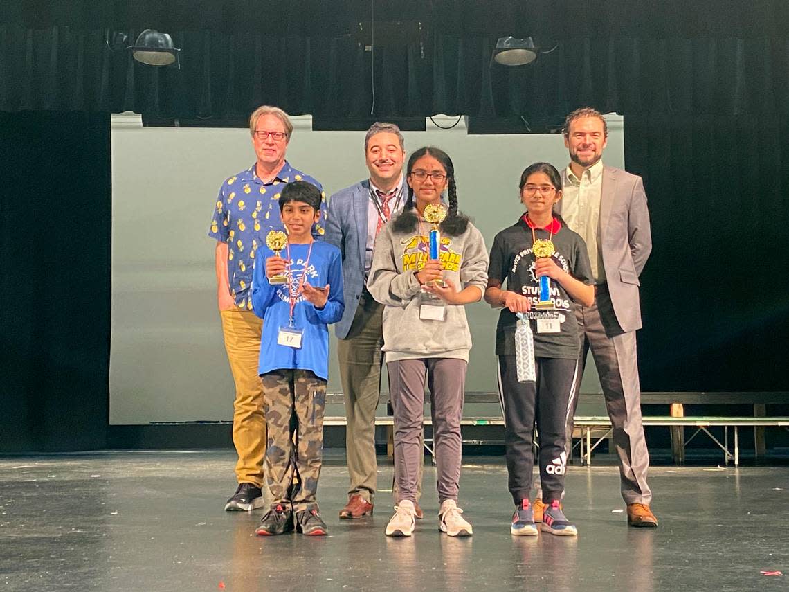 From left, Wake district spelling bee winners Reyansh Joshi, third place, Chaitra Yeccherla, first place, and Ananya Rao Prassanna, second place. To the rear are judges Josh Shaffer and Lars Dolder of The News & Observer, and Chris Cox, announcer and principal of Leesville Road Middle School.