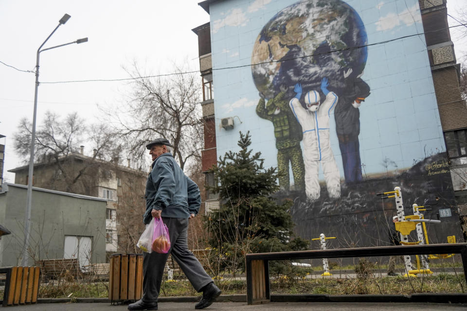 A man walks past a giant poster dedicated to the fight against coronavirus in Almaty, Kazakhstan, Monday, Jan. 10, 2022. Kazakhstan's health ministry says over 150 people have been killed in protests that have rocked the country over the past week. President Kassym-Jomart Tokayev's office said Sunday that order has stabilized in the country and that authorities have regained control of administrative buildings that were occupied by protesters, some of which were set on fire. (Vladimir Tretyakov/NUR.KZ via AP)