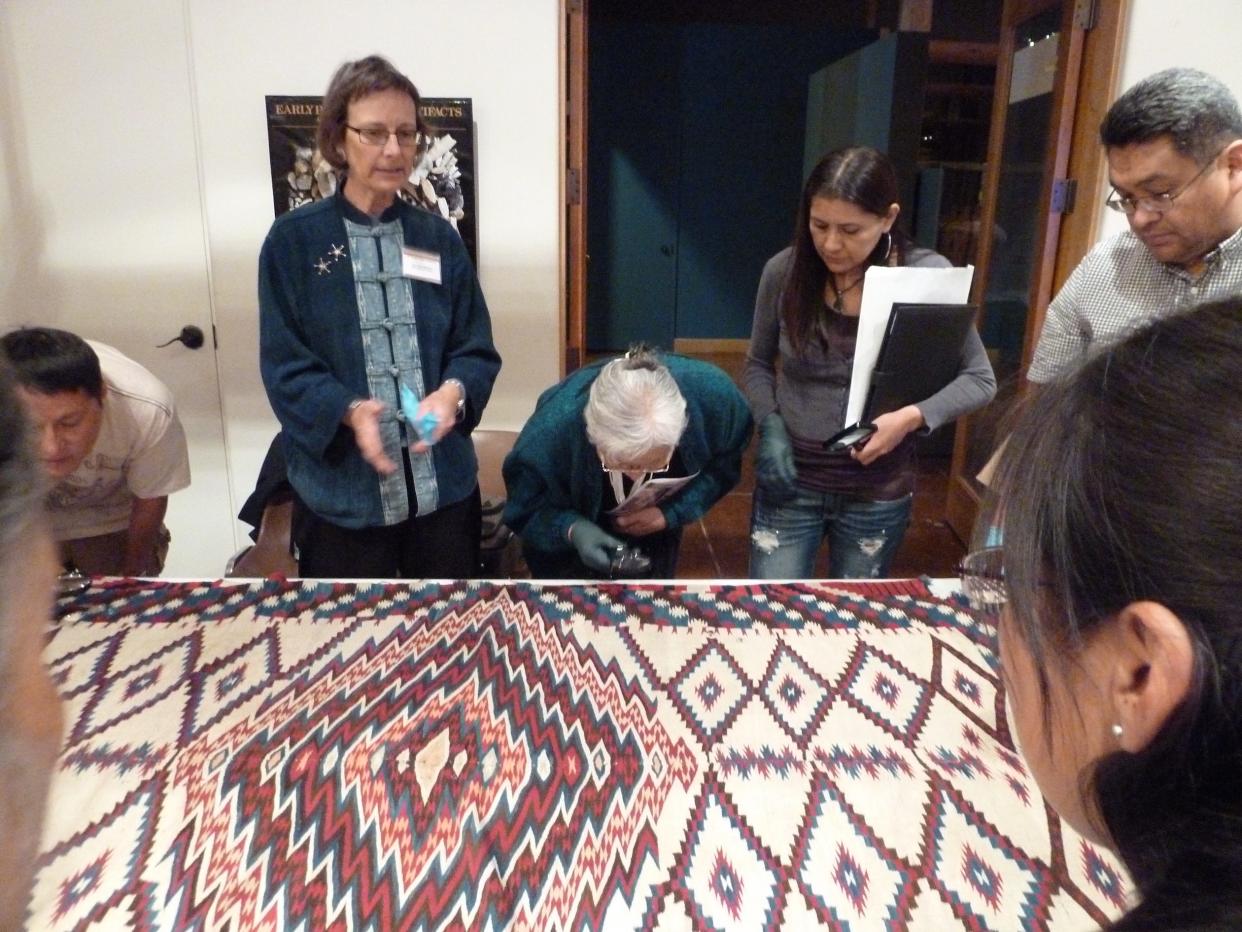 Ann Hedlund, standing at center left, along with Marlowe Katoney, left, Mary Lee Henderson Begay, right, her daughter Gloria Begay, and Belvin Pete examine a 19th century Saltillo sarape from Mexico during a Southwest textile analysis workshop for indigenous Navajo weavers and museum professionals taught by Hedlund, at the Museum of Indian Arts & Culture, Santa Fe, NM, March 17, 2012. All are Navajo/Diné weavers except Pete who is a weaving tool maker.