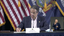 In this image made from video provided by the office of Gov. Andrew M. Cuomo, Gov. Cuomo signs a bill giving death benefits to the families of certain government workers who were killed by coronavirus, Saturday, May 30, 2020 in New York. (Office of Governor Andrew M. Cuomo via AP)