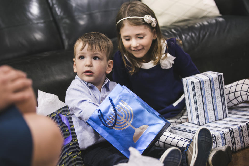 A young brother and sister open Hanukkah presents in their home