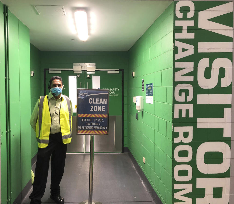 A man guards change rooms at the stadium as the Parramatta Eels and the Brisbane Broncos of the National Rugby League resume play without spectators, Thursday, May 28, 2020, in Brisbane, Australia. Two rounds of matches were played in the NRL in March before Australia and New Zealand went into lockdown and closed borders in a bid to slow the spread of COVID-19. (AP Photo/John Pye)