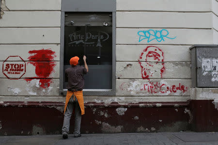 A worker closes the security shutter of a window at Arte Paris cafe in downtown Caracas, Venezuela January 16, 2018. Picture taken January 16, 2018. REUTERS/Marco Bello