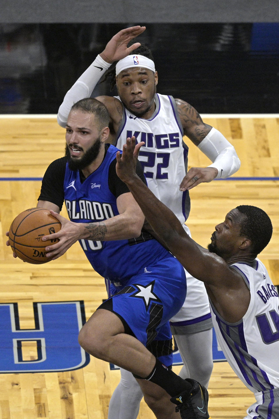 Orlando Magic guard Evan Fournier (10) looks to pass the ball from between Sacramento Kings center Richaun Holmes (22) and forward Harrison Barnes (40) during the second half of an NBA basketball game Wednesday, Jan. 27, 2021, in Orlando, Fla. (AP Photo/Phelan M. Ebenhack)