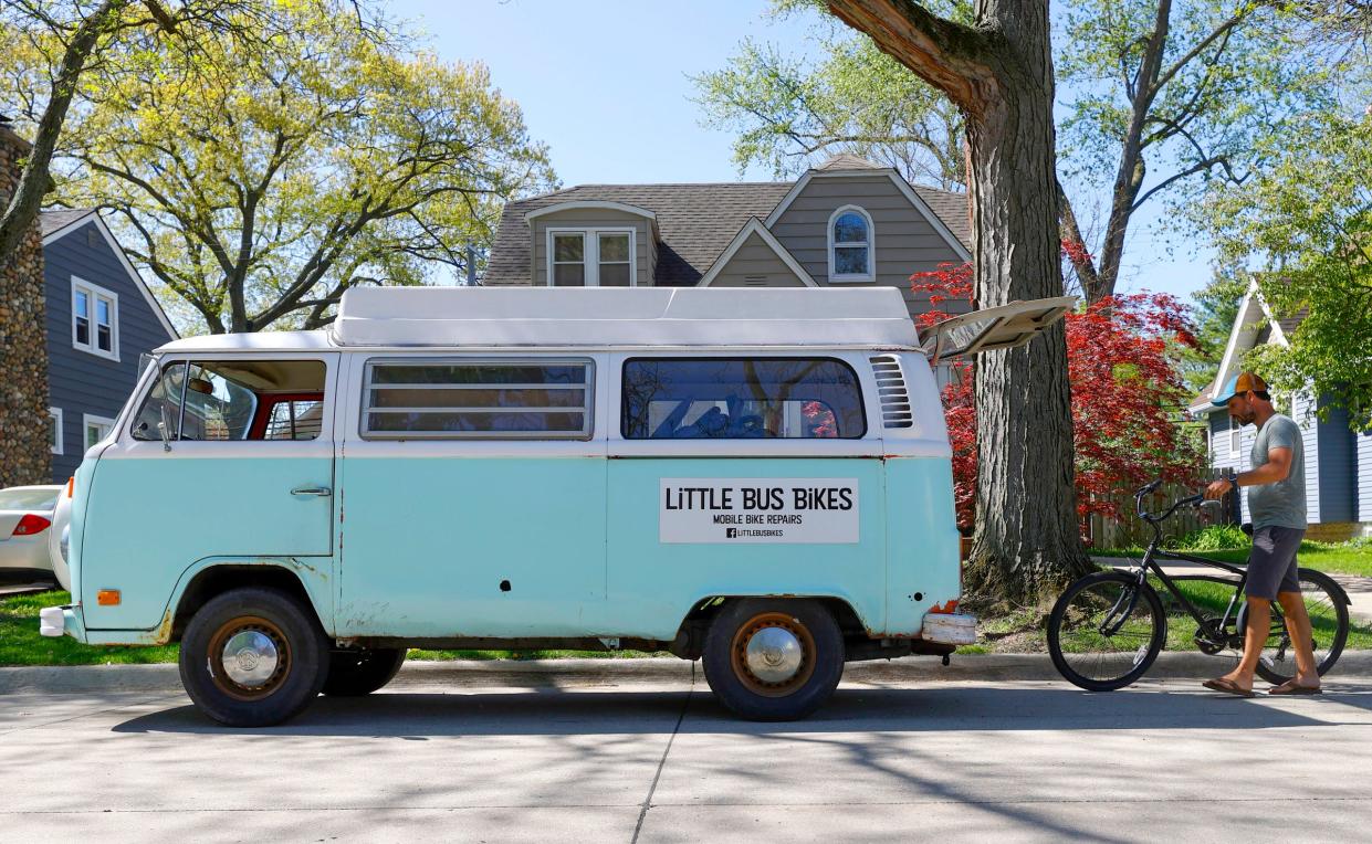 Brian Latulippe, 41 of Royal Oak, takes the bike of Greg Council of Pleasant Ridge towards the back of his VW Bus for a tuneup near Council's house on May 13, 2022.