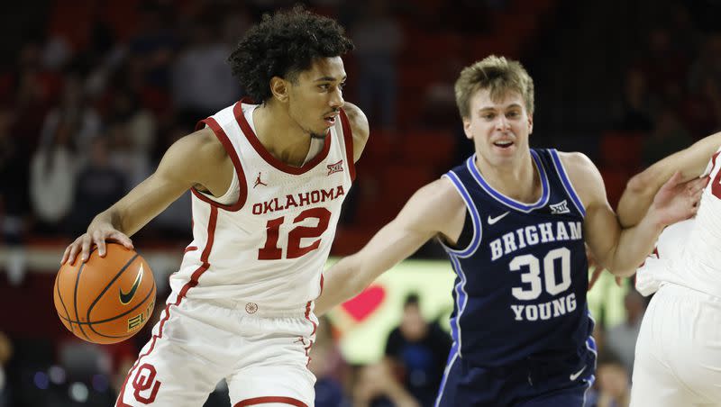 Oklahoma guard Milos Uzan (12) drives the ball away from BYU guard Dallin Hall (30) during the second half of an NCAA college basketball game Tuesday, Feb. 6, 2024, in Norman, Okla. (AP Photo/Garett Fisbeck)