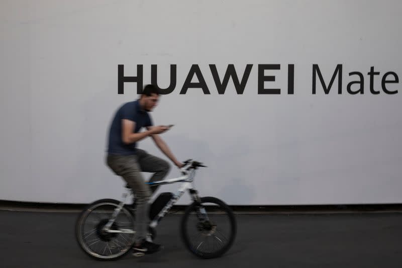 A man rides a bicycle in front of a Huawei billboard in Belgrade