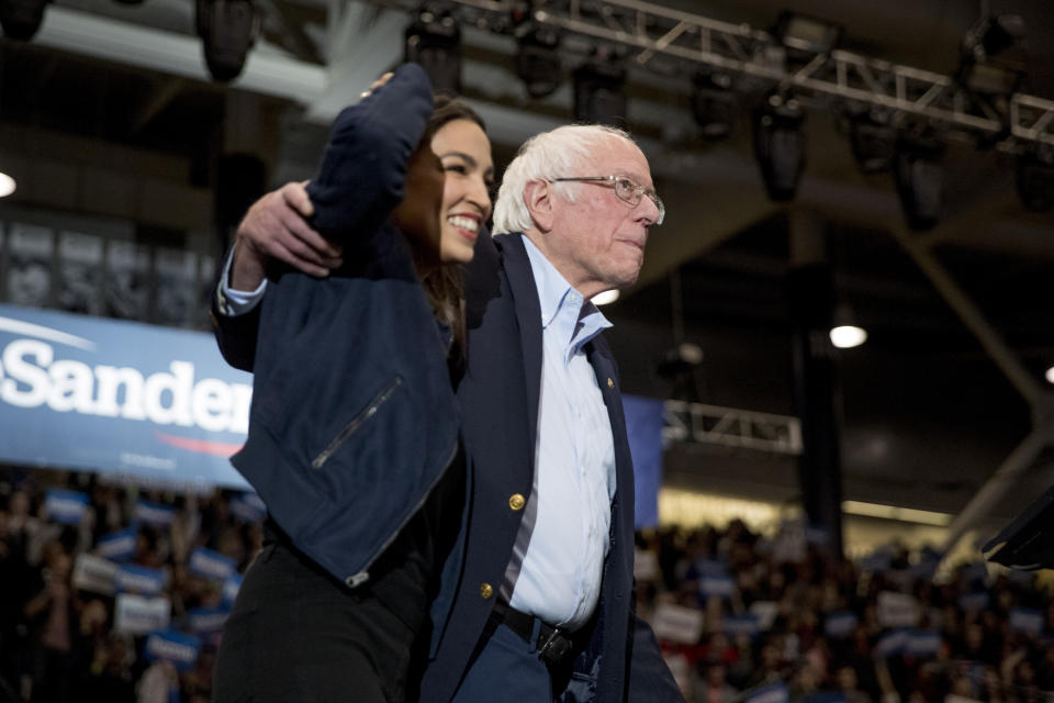 Democratic presidential candidate Sen. Bernie Sanders, I-Vt., accompanied by Rep. Alexandria Ocasio-Cortez, D-N.Y., left, takes the stage at campaign stop at the Whittemore Center Arena at the University of New Hampshire, Monday, Feb. 10, 2020, in Durham, N.H. (AP Photo/Andrew Harnik)