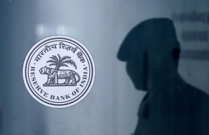 FILE PHOTO: A security guard's reflection is seen next to the logo of the Reserve Bank Of India (RBI) at the RBI headquarters in Mumbai