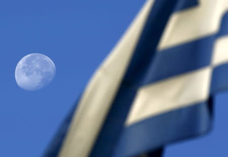 The moon sets behind a Greek flag over an elementary school used as polling station in Athens, Greece July 5, 2015. REUTERS/Yannis Behrakis