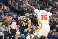 Denver Nuggets guard Jamal Murray, left, looks to pass the ball as Atlanta Hawks center Clint Capela defends in the second half of an NBA basketball game Saturday, Feb. 4, 2023, in Denver. (AP Photo/David Zalubowski)