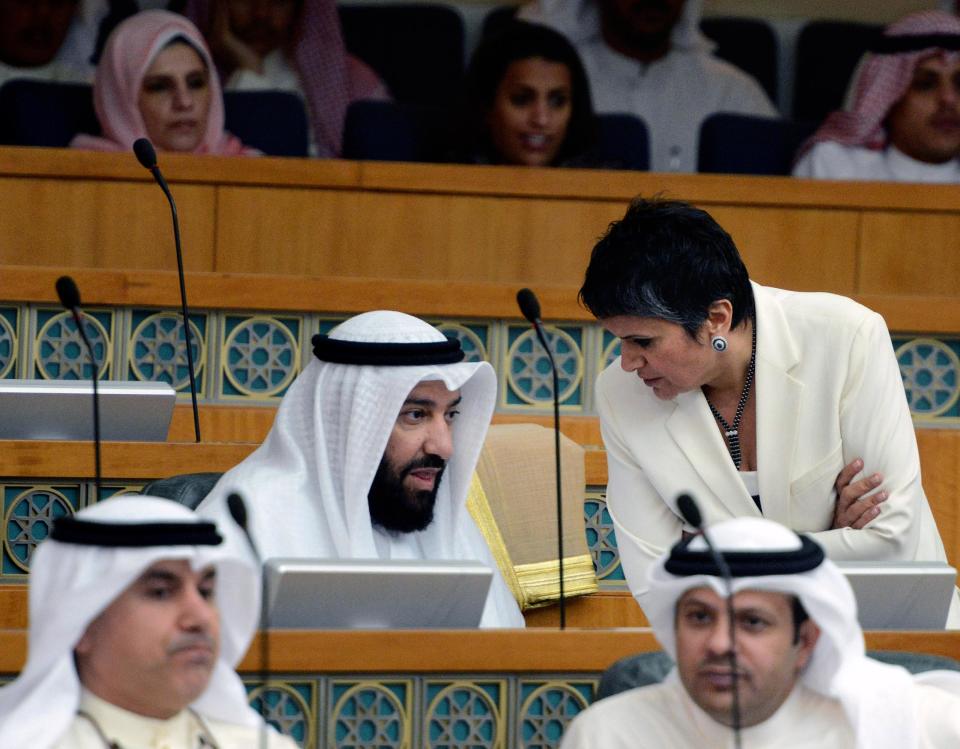 In this Wednesday, Sept. 4, 2013 photo, Kuwaiti MP Ali al-Omair, center, from the Islamist Salafist Alliance, speaks with liberal MP Safa Al Hashem during a National Assembly session in Kuwait. One of the most traditional pleasures of the Middle East _ leisurely puffing on a water pipe filled with aromatic tobacco _ has become ensnared in another of the region's familiar backdrops: Islamic conservatives decrying what they see as liberal decadence. (AP Photo/Gustavo Ferrari)