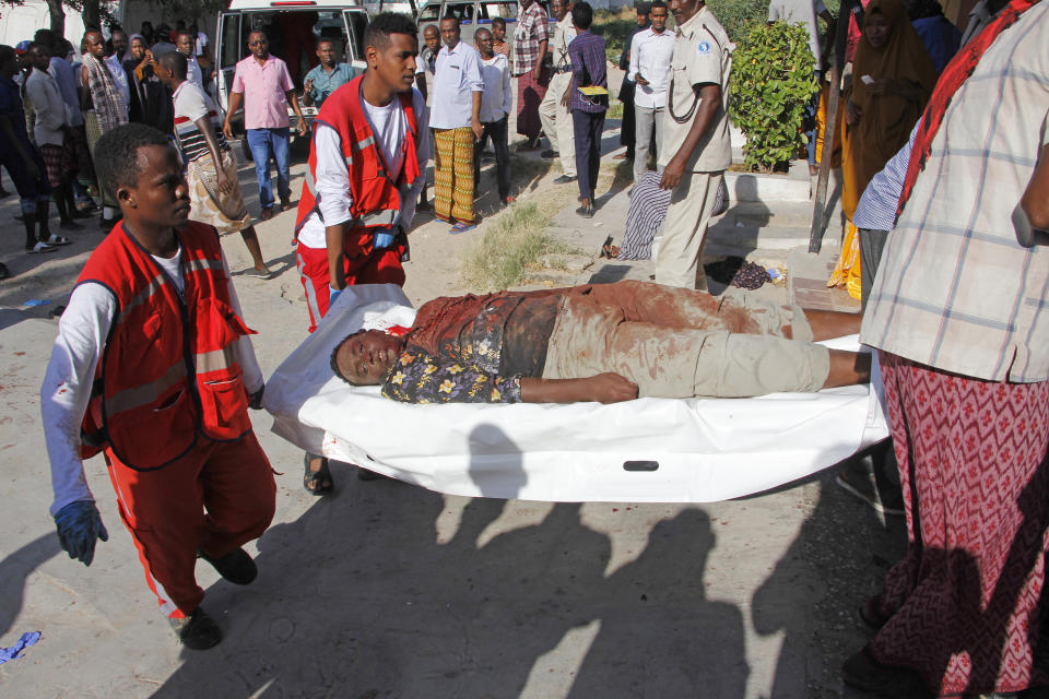 Medical personnel carry a civilian who was wounded in suicide car bomb attack at check point in Mogadishu, Somalia, Saturday, Dec, 28, 2019. A police officer says a car bomb has detonated at a security checkpoint during the morning rush hour in Somalia's capital. (AP Photo/Farah Abdi Warsame)