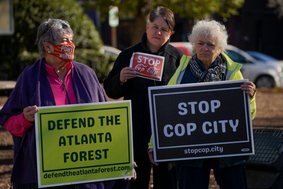 activists hold signs that read defend the atlanta forest and stop cop city