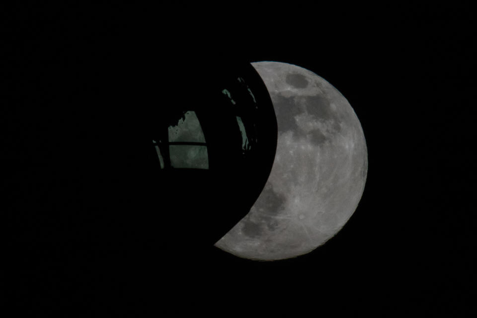 The moon rises behind a pod of the London Eye, ahead of the final supermoon of the year.