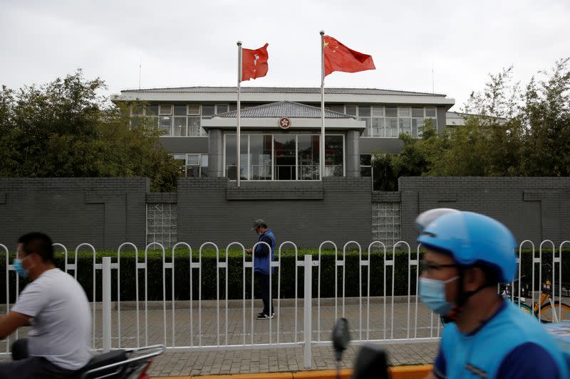 People travel past Chinese and Hong Kong flags in Beijing