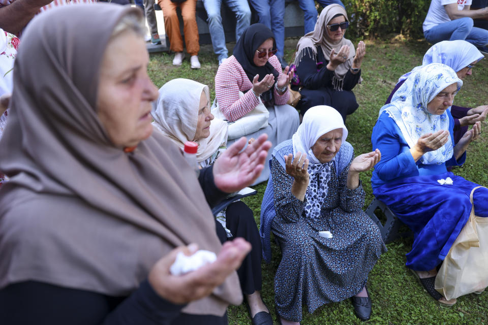 Muslim women pray in Visoko, Bosnia, Sunday, July 9, 2023 next to a truck carrying 30 coffins with remains of the recently identified victims of the 1995 Srebrenica genocide. So far, the remains of more than 6,600 people have been found and buried at a vast and ever-expanding memorial cemetery in Potocari, outside Srebrenica. (AP Photo/Armin Durgut)