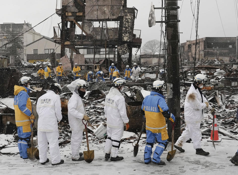 Police officers conduct a search operation in a snow at a burnt market in Wajima, Ishikawa prefecture, Japan Sunday, Jan. 7, 2024. A major earthquake slammed western Japan on Jan. 1, killing scores of people, toppling buildings and setting off landslides. (Kyodo News via AP)