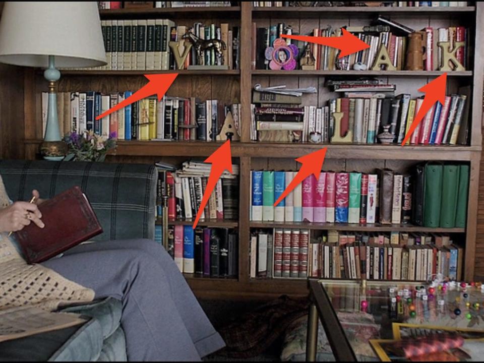 Lorainne sitting in front of the bookshelf that spells out "Valak" in "The Conjuring 2"