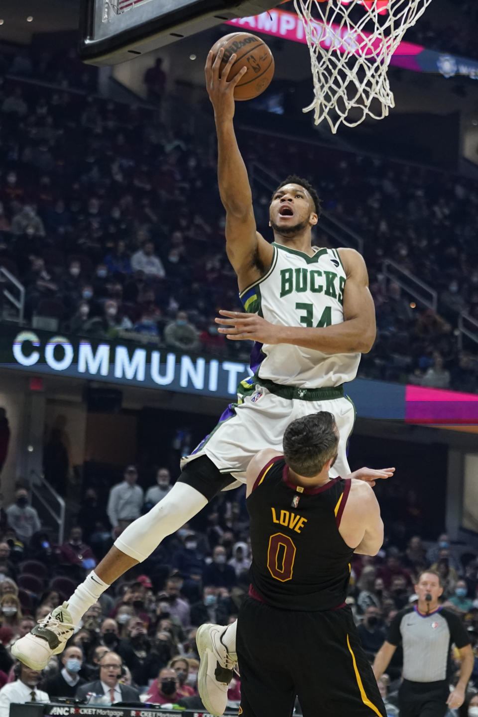 Milwaukee Bucks' Giannis Antetokounmpo (34) drives to the basket over Cleveland Cavaliers' Kevin Love (0) in the first half of an NBA basketball game, Wednesday, Jan. 26, 2022, in Cleveland. Antetokounmpo was called for a foul on the play. (AP Photo/Tony Dejak)