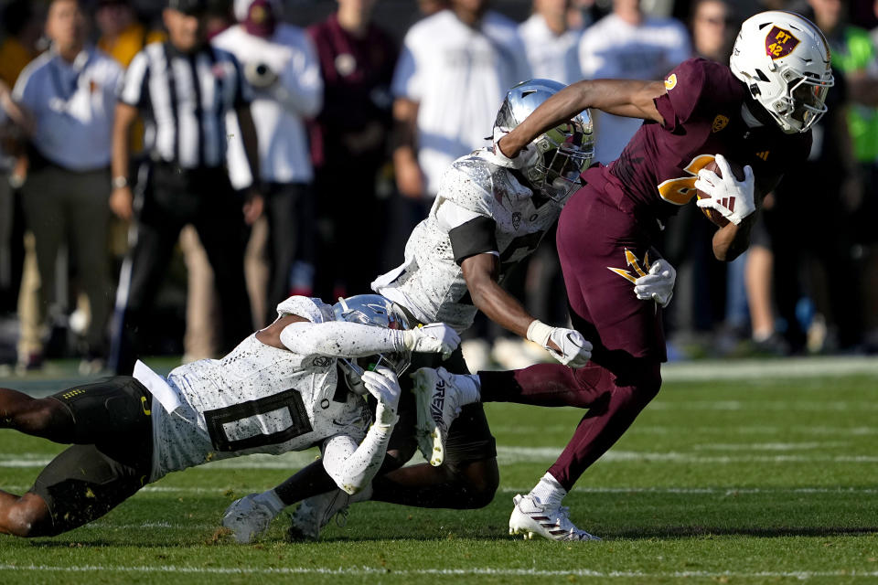 Arizona State wide receiver Elijhah Badger, right, is tackled by Oregon defensive back Tysheem Johnson (0) and defensive back Jahlil Florence during the first half on an NCAA college football game, Saturday, Nov. 18, 2023, in Tempe, Ariz. (AP Photo/Matt York)