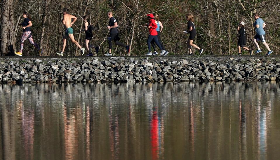 Runners reflect off the lake during the Raise the Roof 5K early Saturday morning, March 4, 2023, at Rankin Lake Park.