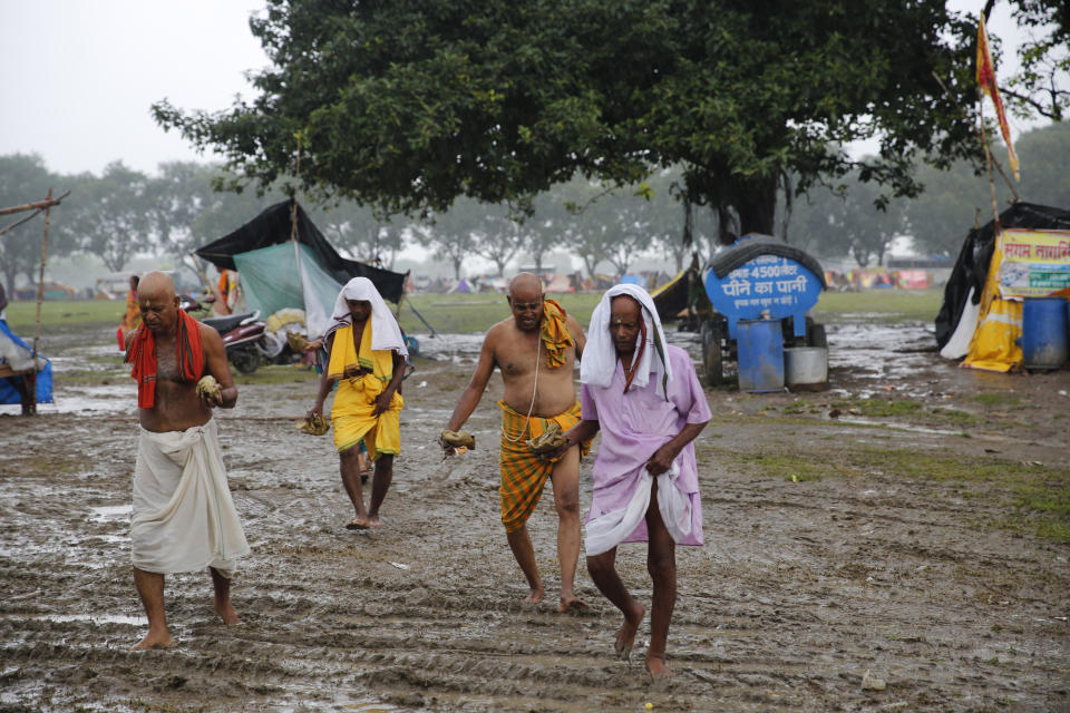 Hindu devotees walk towards the River Ganges to perform rituals on a road made slushy by the rains in Prayagraj, in the northern Indian state of Uttar Pradesh, Saturday, Sept. 28, 2019. A heavy spell of retreating monsoon rains has flooded wide areas in northern India, killing dozens of people this week, an official said Saturday. Sandhaya Kureel, a spokeswoman of the Disaster Management and Relief Department, said most of the 59 fatalities were caused by house collapses, lightning and drowning in Uttar Pradesh state. (AP Photo/Rajesh Kumar Singh)