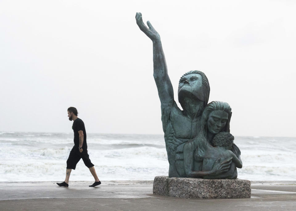 Richard Tumlinson watches waves crash along the seawall as he passes the 1900 storm memorial while rain rollsl in, Wednesday, June 19, 2024, in Galveston, Texas. The statue honors the more than 8,000 people killed in the hurricane called "The Great Storm" in 1900. Tropical Storm Alberto has formed in the southwestern Gulf of Mexico, the first named storm of what is forecast to be a busy hurricane season. (Jason Fochtman/Houston Chronicle via AP)