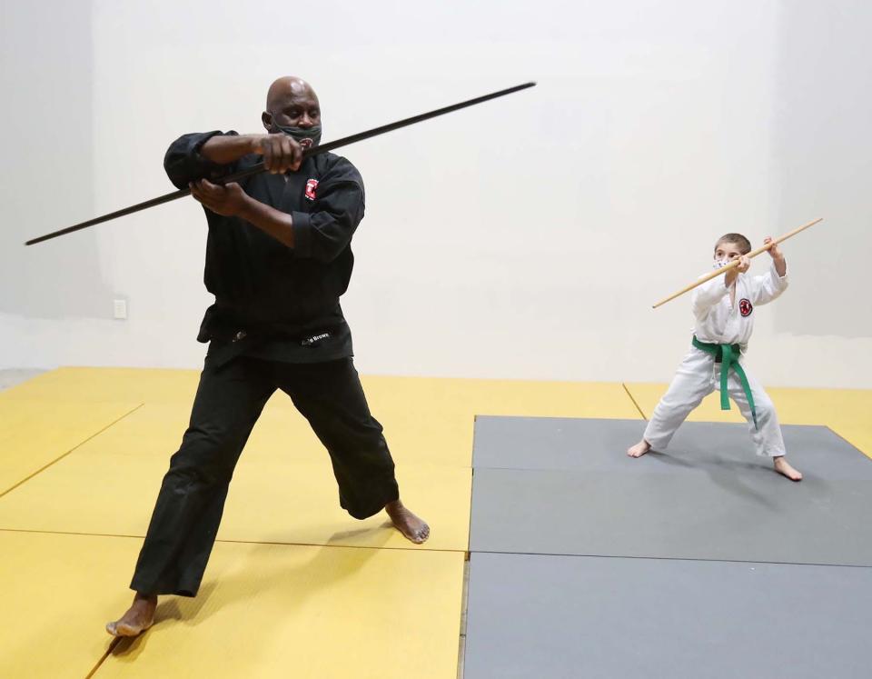 Reggie Brown, the owner and sensei of the Twinsburg Karate Institute, works with student Carter Roesel, 8, on learning the basics of bo kata.