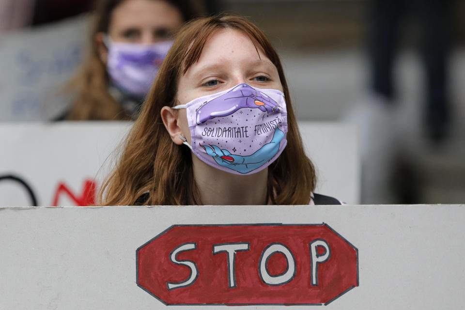 Women, wearing masks against the COVID-19 infection that read "Feminist Solidarity", hold banners during a protest in Bucharest, Romania, Sunday, Oct. 25, 2020, against rising levels of violence against women and the ineffectiveness of restraining orders during and after the lockdown period imposed by authorities to control the pandemic. Romania, a European Union member state, has no proper legal framework to combat domestic violence against women, with police unable to intervene if acts of violence inside a couple's home. (AP Photo/Vadim Ghirda)