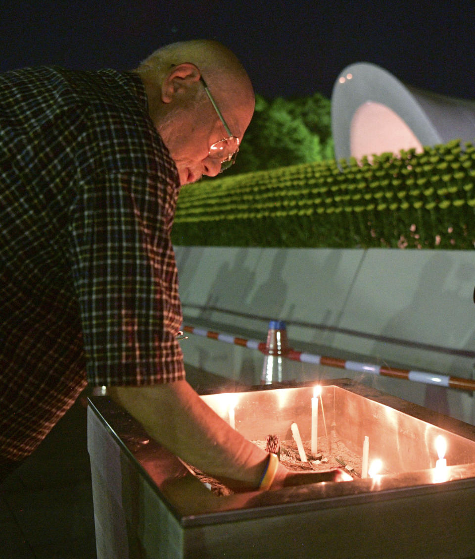 A man burns a stick of incense at the cenotaph dedicated to the victims of atomic bombing at Hiroshima Peace Memorial Park in Hiroshima, western Japan, early Monday, Aug. 6, 2018, marking the 73rd anniversary of the bombing. (Yohei Nishimura/Kyodo News via AP)