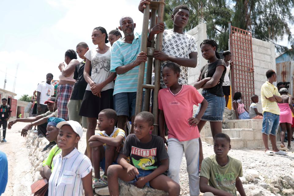 Locals stand around after people were killed during a religious march against a criminal gang in Canaan at Tabare, in the district of Port-au-Prince, Haiti, Sunday, Aug. 27, 2023. The powerful gang opened fire on the large group of parishioners as they marched through the community led by a pastor and armed with machetes in an attempt to rid the area of its presence.