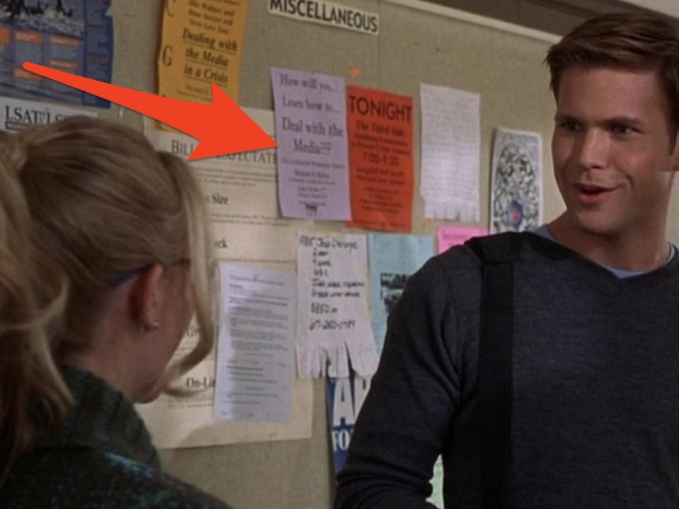 red arrow pointing at flyers on a bulletin board behind elle and warren in a scene from legally blonde