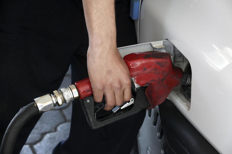 A gas station worker fills a car in central Tehran, Iran, Friday, April 25, 2014. The Iranian government on Friday cut a portion of fuel subsidies, nearly doubling some prices at the pump as part of a second round of cuts delayed since 2012. (AP Photo/Vahid Salemi)
