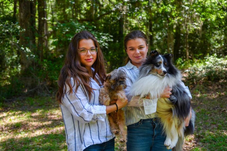 Identical twins Addison Lancaster, left and her sister Kadence Lancaster, both 15-years old, pose for a photo with their favorite dogs. Addison holds Humphrey, a 6-year old Affenpinscher and Kadence holds Levi, a 6-year old Blue Merle Sheltie.