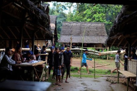 Baduy people queue to cast their vote as others carry tree trunks in front of a polling station during regional elections at Kanekes village in Rangkasbitung, Banten province, Indonesia, June 27, 2018. REUTERS/Beawiharta