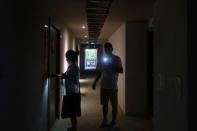 Ma Mao, 41, a businessman from Shanxi Province, illuminates with his cellphone as his assistant opens a room in one of his newly bought apartment buildings developed by Sunac China Holdings, in Xishuangbanna, Yunnan