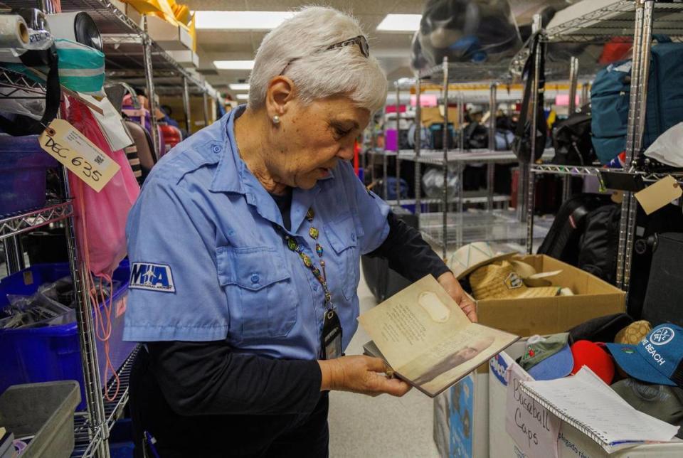 Terminal Operations specialist, Concha Gilles displays a book in Hebrew language left behind and stored at the Lost and Found department at Miami International Airport, till the owner claim it, on Tuesday December 13, 2023.