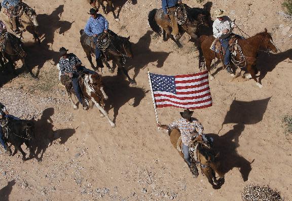 FILE - In this April 12, 2014, file photo, the Bundy family and their supporters fly the American flag as their cattle is released by the Bureau of Land Management back onto public land outside of Bunkerville, Nev. A federal judge in Nevada is considering crucial rulings about what jurors will hear in the trial of six defendants accused of stopping U.S. agents at gunpoint from rounding up cattle near Cliven Bundy's ranch in April 2014. (Jason Bean/Las Vegas Review-Journal, via AP, File)