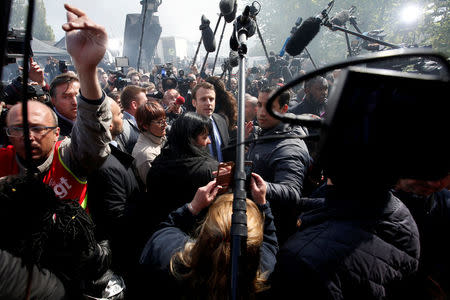 Emmanuel Macron (C), head of the political movement En Marche !, or Onwards !, and candidate for the 2017 French presidential election, is surrounded by journalists as he arrives to meet Whirlpool employees in front of the company plant in Amiens, France, April 26, 2017. REUTERS/Pascal Rossignol