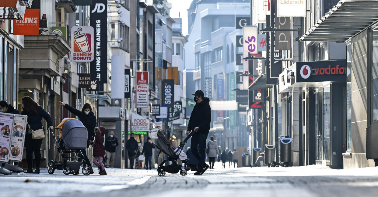 People walk on the main shopping street in Cologne Germany, Wednesday, Dec. 16, 2020. Germany has entered a harder lockdown, closing shops and schools in an effort to bring down stubbornly high new cases of the coronavirus. (AP Photo/Martin Meissner)