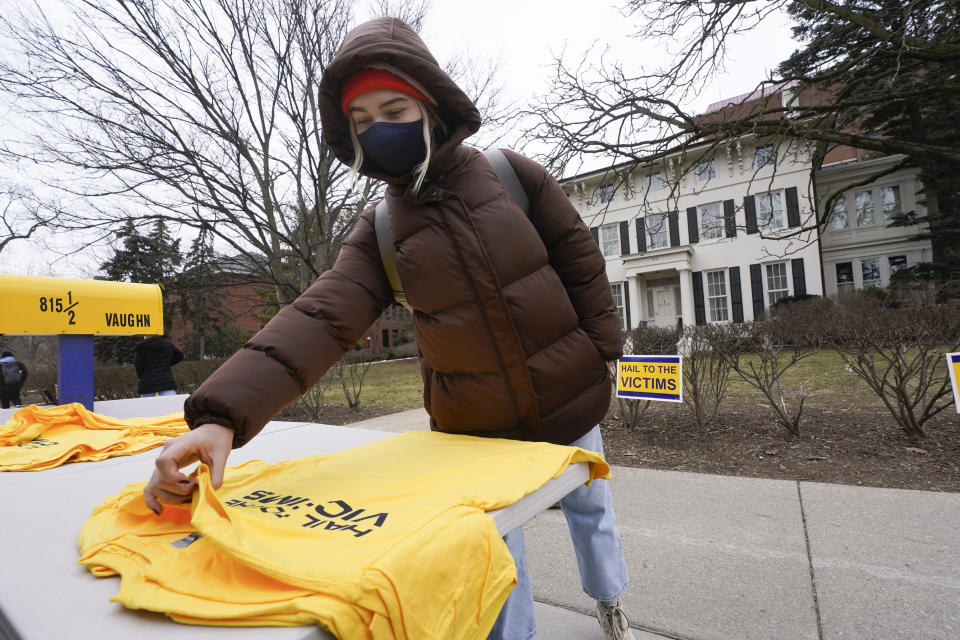 Student Kate George picks up a Hail To The Victims t-shirt outside the University of Michigan's Presidents House on campus in Ann Arbor, Mich., Thursday, Jan. 20, 2022. (AP Photo/Paul Sancya)