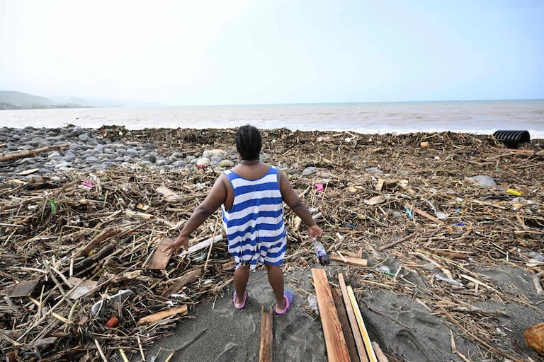 Una mujer observa una playa llena de basura en Bull Bay, Jamaica, tras el paso del huracán Beryl el 4 de julio de 2024. Beryl se dirigió hacia México y las Islas Caimán a primera hora del 4 de julio, amenazando con fuertes vientos y una marejada ciclónica tras azotar la costa sur de Jamaica.