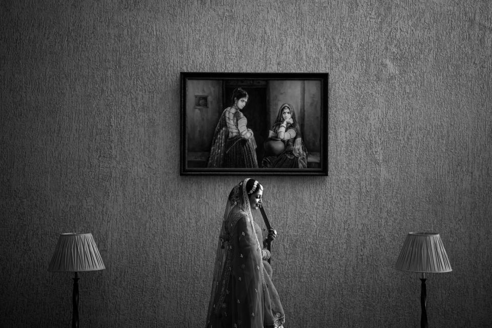 A photo of a bride beneath a portrait on the wall