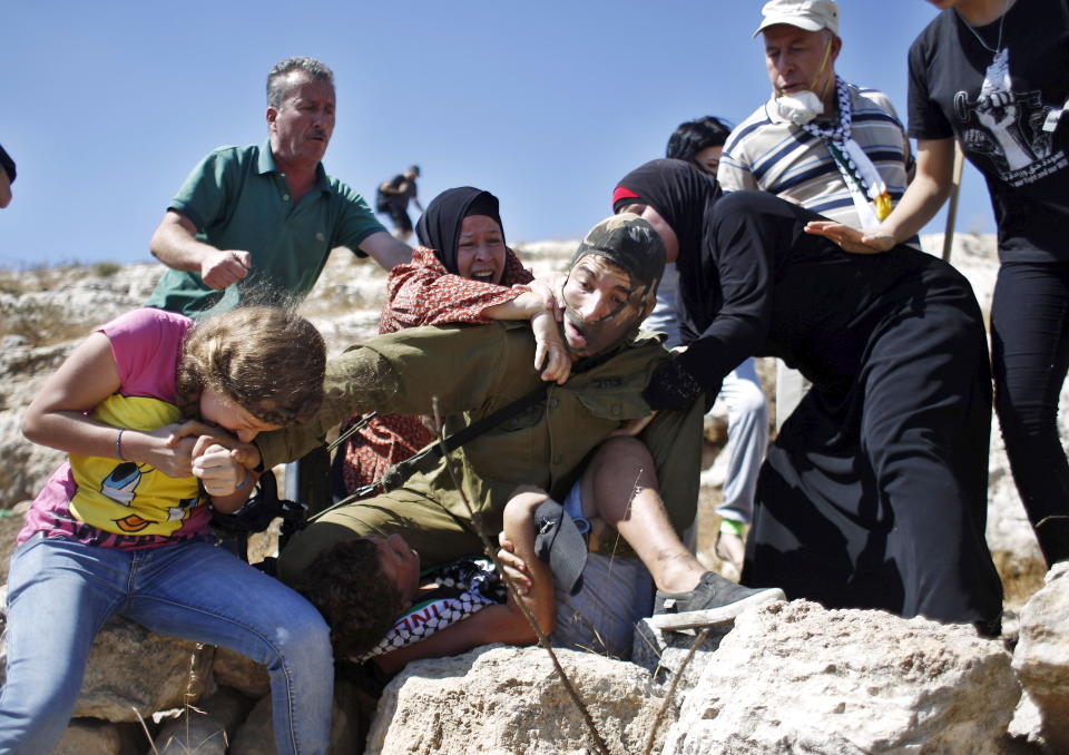 Palestinians scuffle with an Israeli soldier 