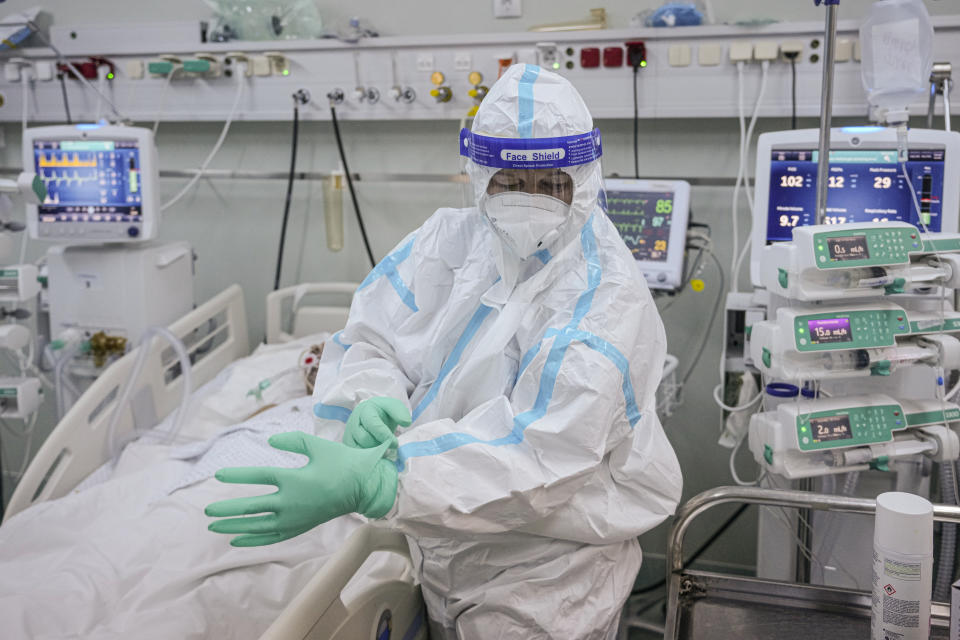 A member of the medical staff puts on an extra pair of gloves in the COVID-19 ICU unit of the Marius Nasta National Pneumology Institute in Bucharest, Romania, Thursday, Sept. 23, 2021. Daily new coronavirus infections in Romania, a country of 19 million, have grown exponentially over the last month, while vaccine uptake has declined to worrying lows. Government data shows that 91.5% of COVID-19 deaths in Romania between Sept. 18-23 were people who had not been vaccinated. (AP Photo/Vadim Ghirda)