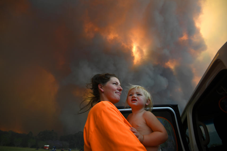 Sharnie Moren and her 18-month-old daughter Charlotte with a backdrop of thick smoke. 