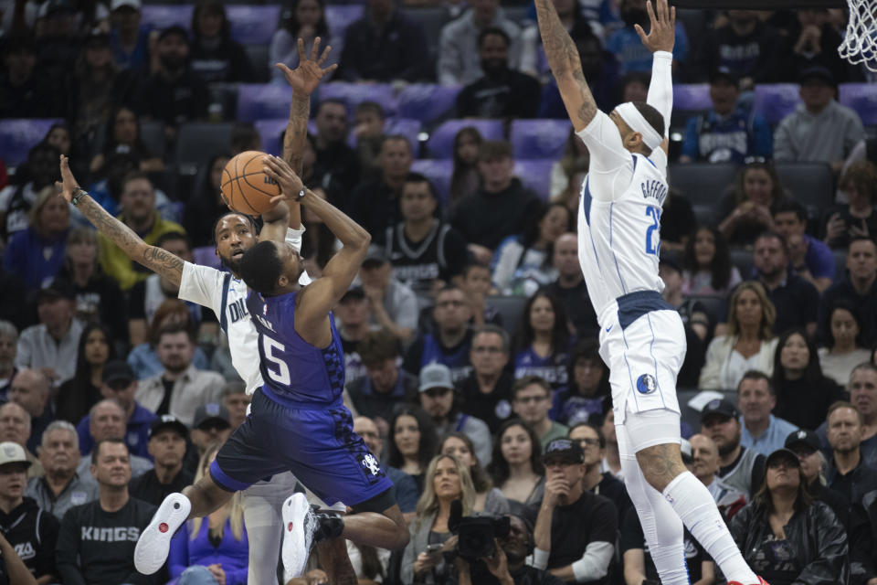 Sacramento Kings guard De'Aaron Fox (5) shoots as Dallas Mavericks forward Derrick Jones Jr. and center Daniel Gafford (21) defend during the first half of an NBA basketball game in Sacramento, Calif., Tuesday, March 26, 2024. (AP Photo/José Luis Villegas)